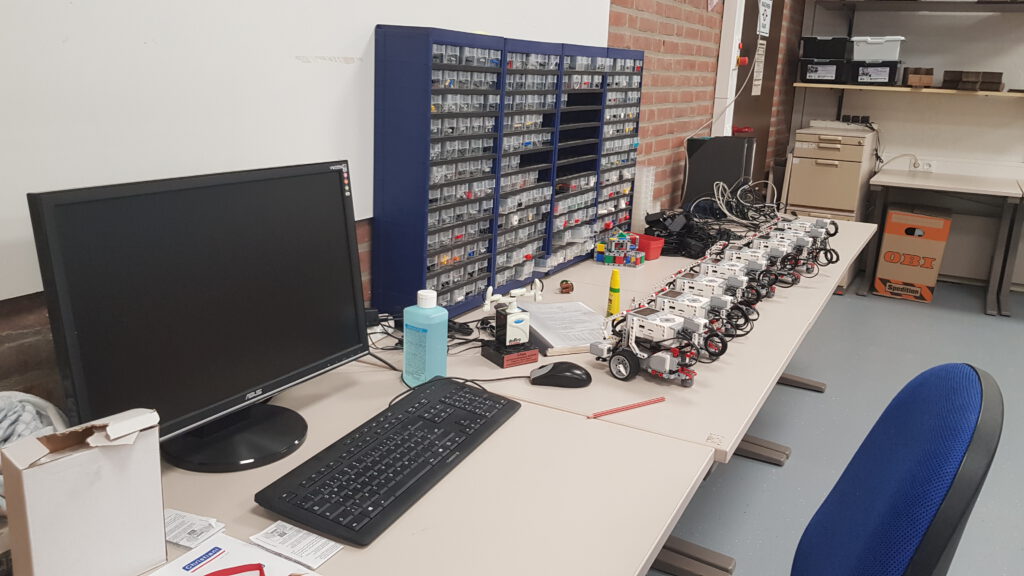 Lego-Roboter stehen bereit zum Laden vor den Ersatzteilkisten